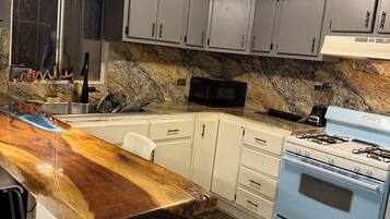 Una cocina con encimera de madera, estufa a gas, armarios y microondas.