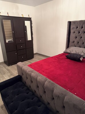 A bedroom with a bed, a wardrobe, and a red throw on the bed.