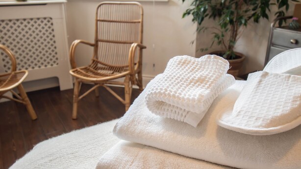 Une pièce avec un canapé blanc, un fauteuil en osier et une plante en pot.