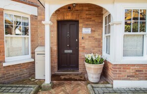 A brick house with a dark brown front door, a mailbox, and a flower pot with white flowers. - Vereeniging Holiday Home (Seaford)