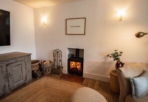 A cozy living room with a fireplace, a mounted picture frame with text, and a decorative wall sconce. - Vereeniging Holiday Home (Seaford)