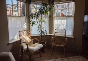 A room with two wicker chairs, one with a white furry seat, and a large potted plant in the corner. - Vereeniging Holiday Home (Seaford)