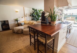 A modern kitchen with a wooden island, bar stools, and a dining area with a sofa. - Vereeniging Holiday Home (Seaford)