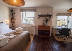 A hotel room with a bed, a desk, a chair, a radiator, and a window with a view. - Vereeniging Holiday Home (Seaford)