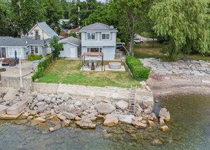 A residential property with a house, a yard, and a rocky shoreline.