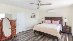 A bedroom with a bed, nightstands, a dresser, a ceiling fan, and a door. - Lake Erie Waterfront | SaluSpa Hot Tub + Fire Pit (Haldimand)