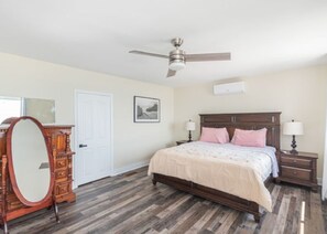 Ein Schlafzimmer mit Bett, Nachttischen, Kommode, Deckenventilator und Tür.