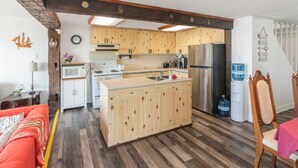 A kitchen with wooden cabinets, a central island, a refrigerator, and a microwave. - Lake Erie Waterfront | SaluSpa Hot Tub + Fire Pit (Haldimand)