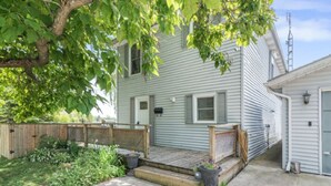 A residential property with a front porch, a small garden, and a wooden fence. - Lake Erie Waterfront | SaluSpa Hot Tub + Fire Pit (Haldimand)