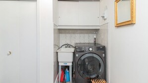 A compact laundry room with a washing machine, a sink, and a drying rack. - Lake Erie Waterfront | SaluSpa Hot Tub + Fire Pit (Haldimand)