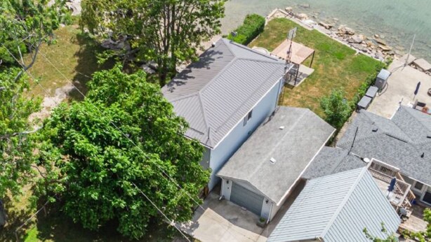 A residential area with houses, a tree, and a body of water. - Lake Erie Waterfront | SaluSpa Hot Tub + Fire Pit (Haldimand)