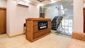 A reception desk with a sign indicating it's company-serviced, a ceiling fan, an air conditioning unit, and a staircase leading to an outdoor area.