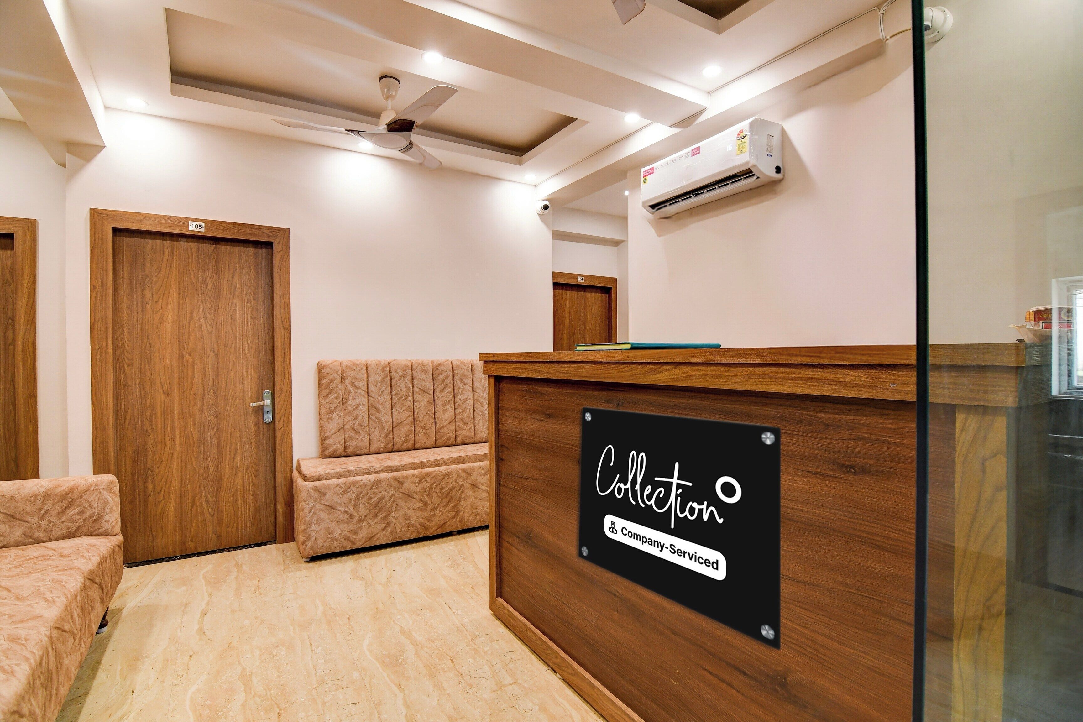 A reception area with a wooden reception desk, a seating area with a cushioned bench, and a ceiling fan.