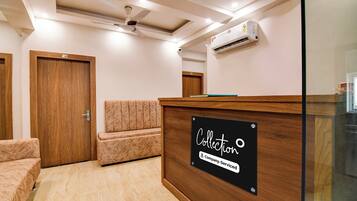 A reception area with a wooden reception desk, a seating area with a cushioned bench, and a ceiling fan.