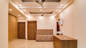 A hotel room with a wooden floor, a sofa, a desk, and a ceiling fan.