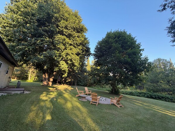 A backyard with a wooden deck, a fire pit, and Adirondack chairs. - Trail 9 Hideaway (Newberry)
