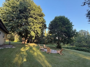 A backyard with a wooden deck, a fire pit, and Adirondack chairs. - Trail 9 Hideaway (Newberry)