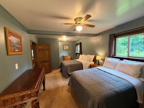 A bedroom with two beds, a ceiling fan, a window, and a door.