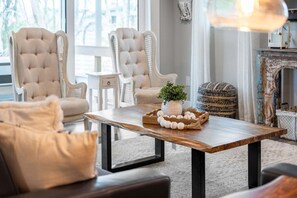 Una sala de estar con una mesa de centro de madera, dos sillones, un sofá y una planta decorativa.