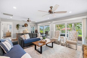 A spacious living room with a sofa, armchairs, a coffee table, and a ceiling fan. - Tropical Riverfront Oasis • Dock • BBQ • Outdoor Patio 🍹 (Melbourne)
