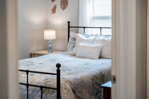 A bedroom with a bed, pillows, a nightstand, a lamp, and wall art. - Tropical Riverfront Oasis • Dock • BBQ • Outdoor Patio 🍹 (Melbourne)