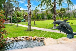 Un jardin paisible agrémenté d’un élément aquatique, notamment un bassin et une statue de dauphins.