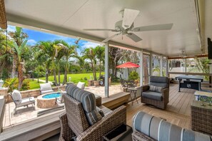 A covered outdoor patio with wicker furniture, a pool, and a view of a lush garden. - Tropical Riverfront Oasis • Dock • BBQ • Outdoor Patio 🍹 (Melbourne)