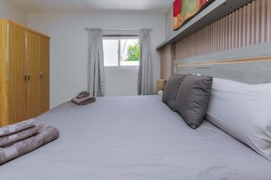 A hotel room with a bed, a wardrobe, a window with curtains, and a painting on the wall. - Modern 1 Bedr Apartment · Stylish Aruba Stay (Noord)