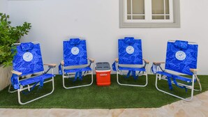 Três cadeiras de praia com um logotipo, um cooler e um vaso de planta.