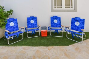 Three beach chairs with a logo, a cooler, and a potted plant. - Modern 1 Bedr Apartment · Stylish Aruba Stay (Noord)