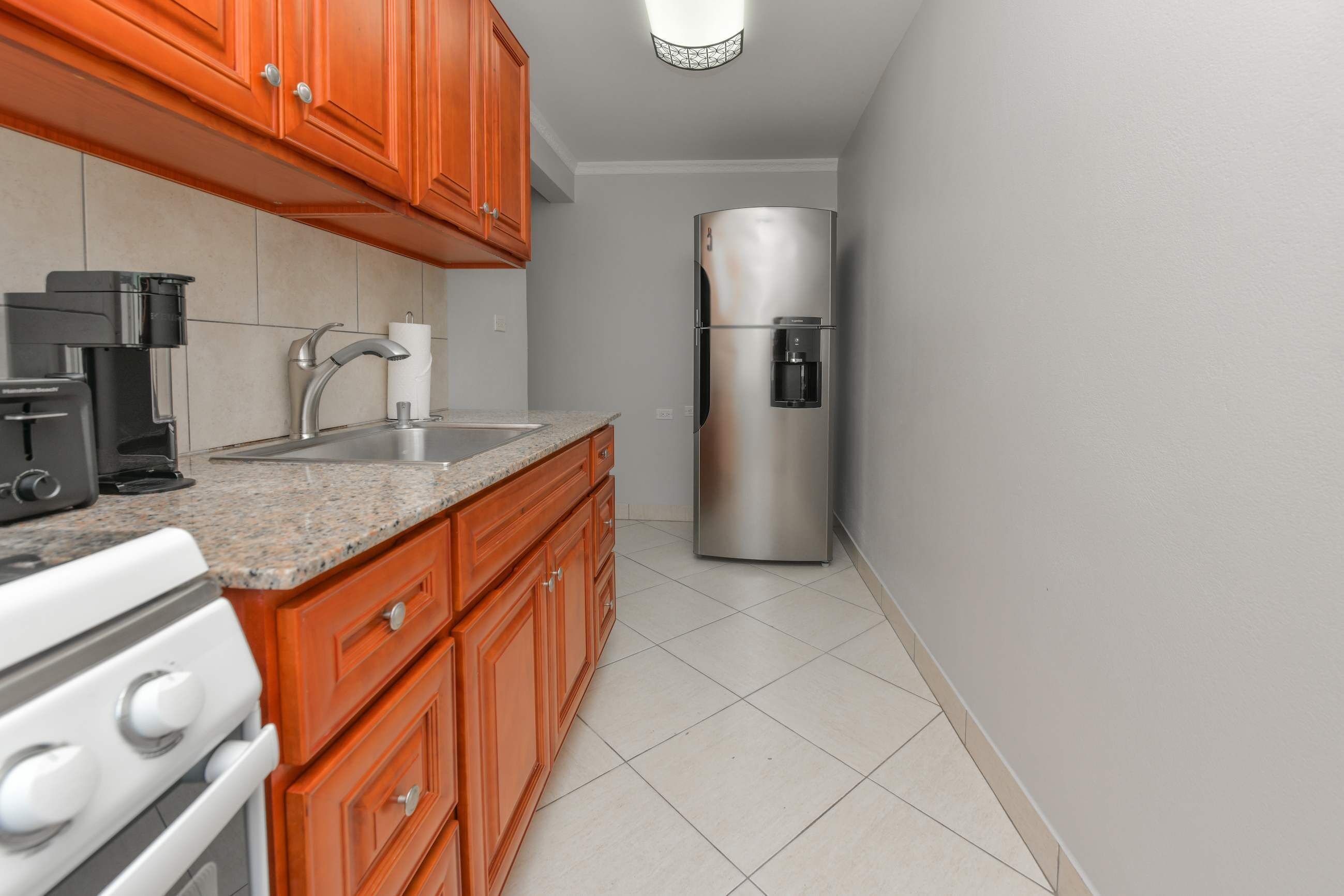 A kitchen with a stainless steel refrigerator, a coffee maker, and a stove.