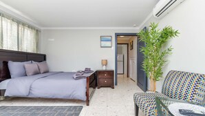 Ein Hotelzimmer mit Bett, Nachttisch, Lampe, Stuhl und einem kleinen Tisch mit Fernbedienung.