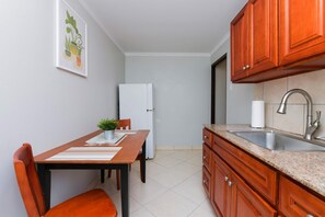 Eine kleine Küche mit Holzausstattung, einem Edelstahlspülbecken und einem weißen Kühlschrank.