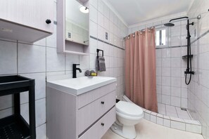 Uma casa de banho moderna com sanita, lavatório e chuveiro.