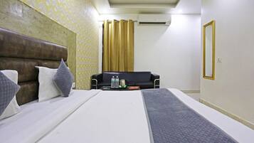 Una habitación de hotel con una cama, un sofá, una mesa de centro con bebidas y un equipo de aire acondicionado.