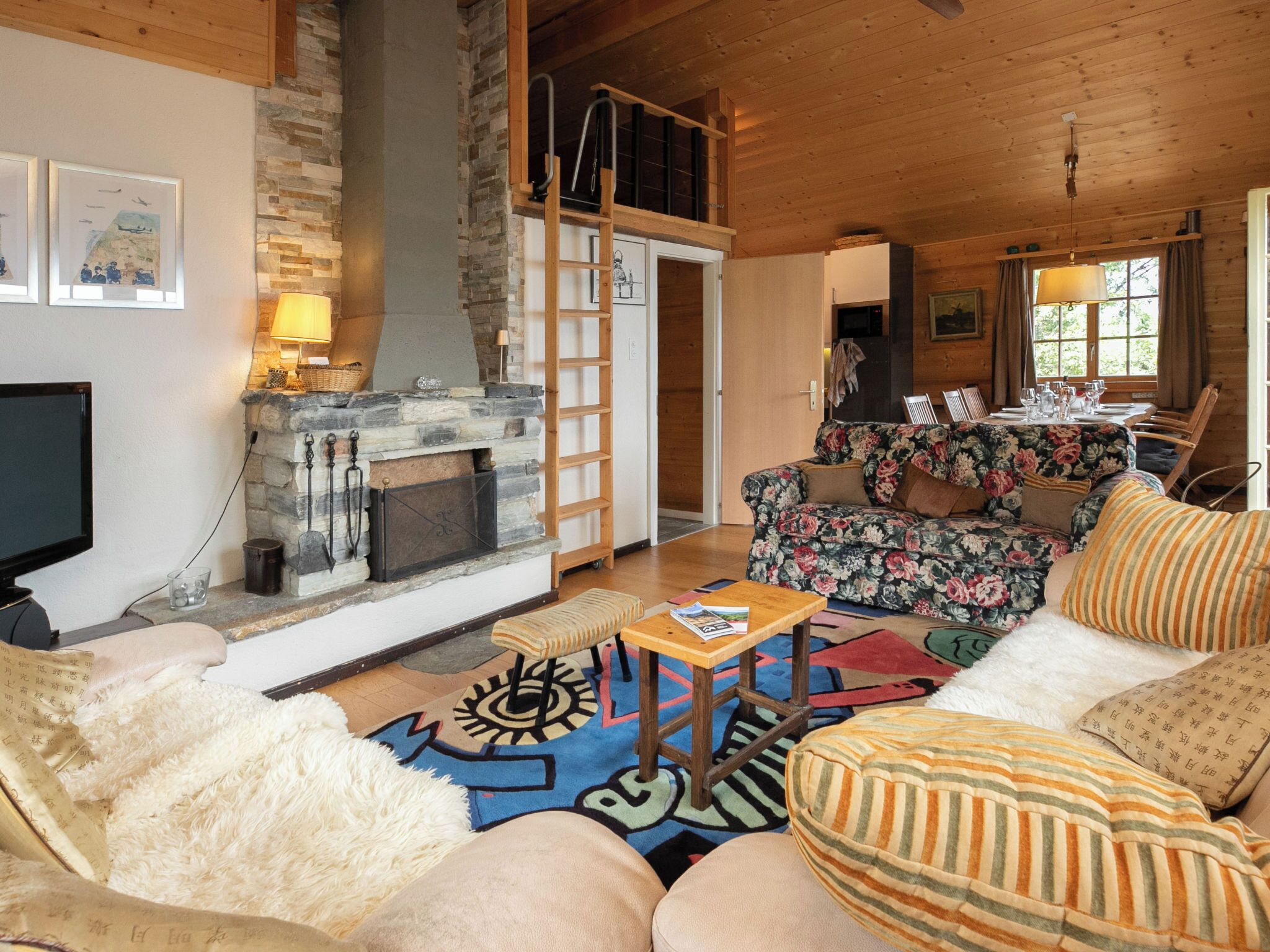 A cozy living room with a fireplace, a television, and a dining area with a table set for two.
