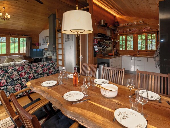 Comedor con una gran mesa de madera dispuesta para seis personas, rodeada de sillas de madera.