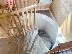 Una escalera de madera que lleva a una habitación con pared blanca y ventana.
