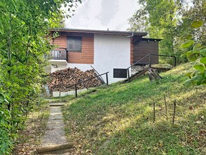 Ein Haus mit Holzfassade, einem sichtbaren Schornstein und einem Holzstapel.