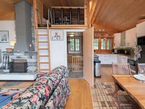 Ein gemütliches Blockhaus mit Kamin aus Stein, einer Holztreppe, einem Essbereich und einer Küche.
