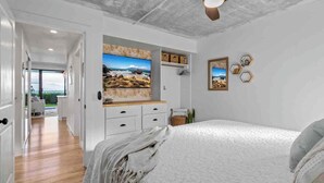 Ein Schlafzimmer mit Bett, Schreibtisch und Blick ins Freie.