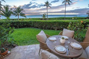 A table set for two with a view of the ocean and palm trees. - Ma'alaea Ocean Front • Whales, Pool & Hot Tub (Wailuku)