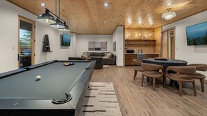 A modern living room with a pool table, a sofa, and a dining area with chairs. - 2 Cabin Retreat/Pool/2HotTubs/Playground/Sleeps 22 (Sevierville)