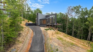 A modern house with a sloped driveway leading to a wooden deck. - 2 Cabin Retreat/Pool/2HotTubs/Playground/Sleeps 22 (Sevierville)