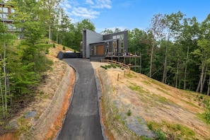 A modern house with a sloped driveway leading to a wooden deck. - 2 Cabin Retreat/Pool/2HotTubs/Playground/Sleeps 22 (Sevierville)