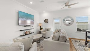 A living room with a flat-screen TV, a ceiling fan, and a large window with blinds. - Easy Days at Lost Bay - 3BDR (Orange Beach)