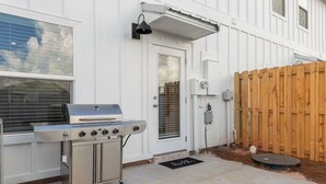 A backyard with a barbecue grill, a wooden fence, and a door with a window. - Easy Days at Lost Bay - 3BDR (Orange Beach)