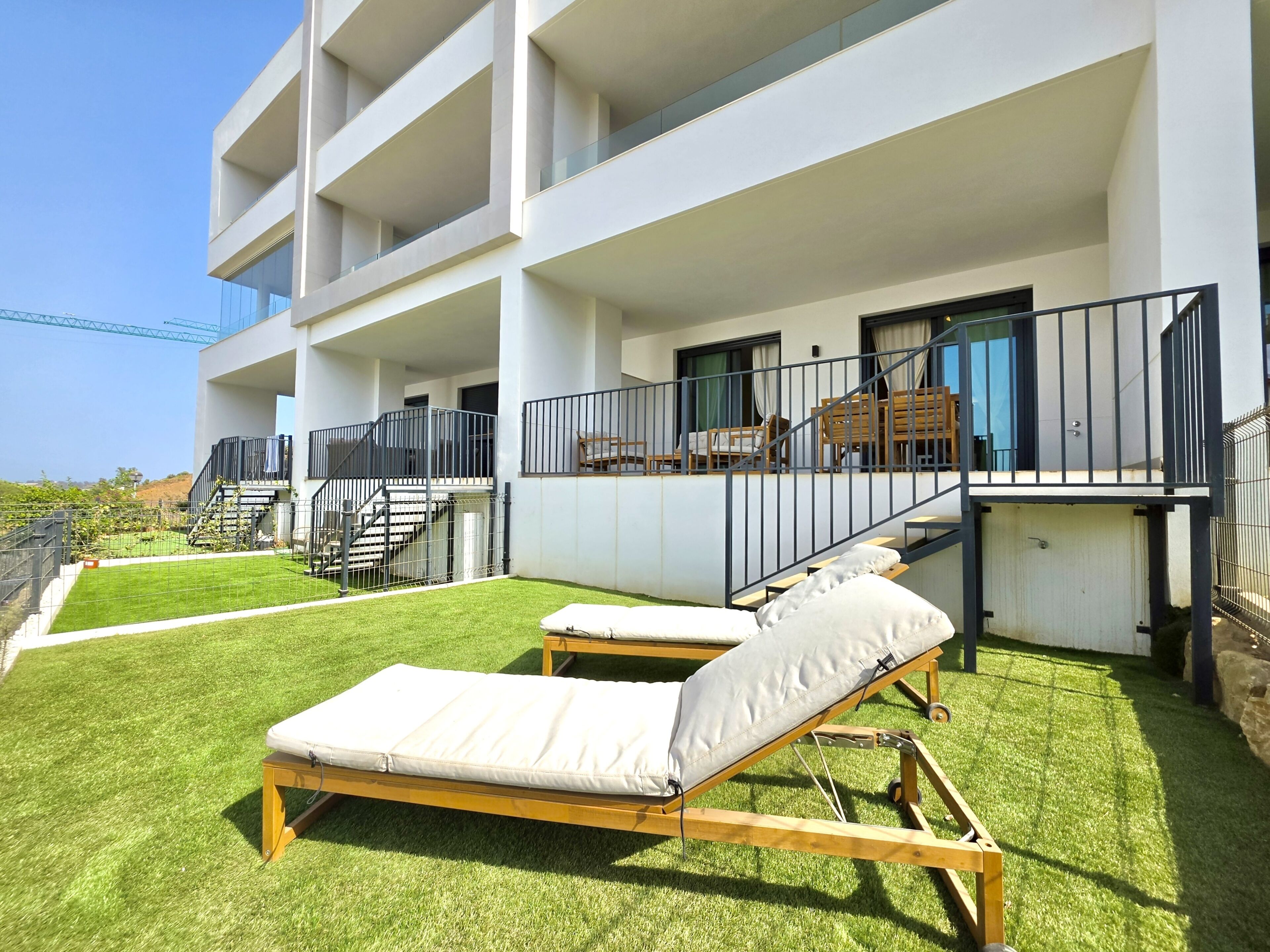 A modern building with a balcony, outdoor furniture, and a grassy area.