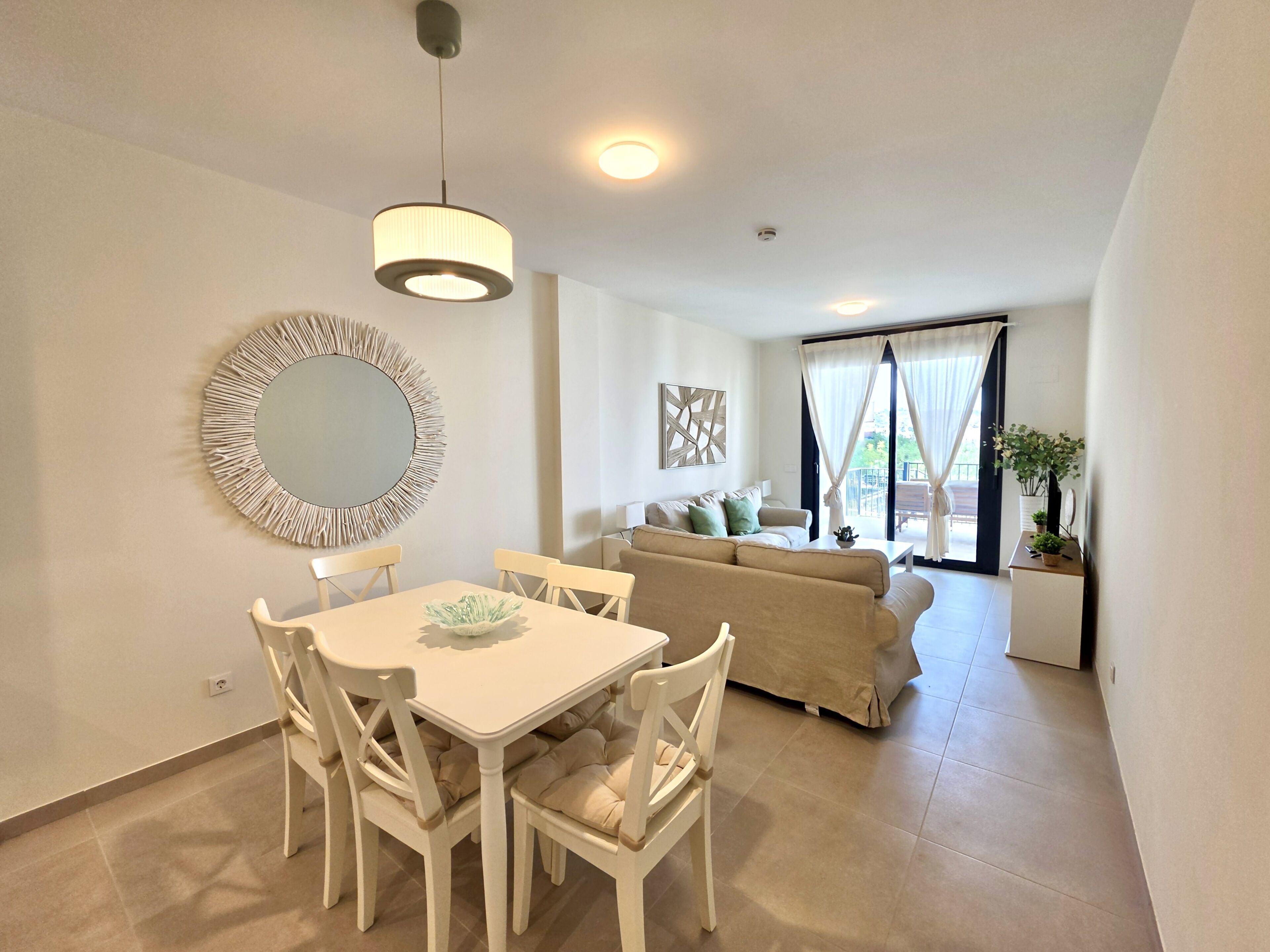 A modern living room with a dining area, a sofa, and a large mirror on the wall.