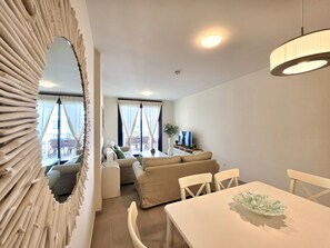 Ein modernes Wohnzimmer mit einer Couch, einem Esstisch und einem Fernseher.